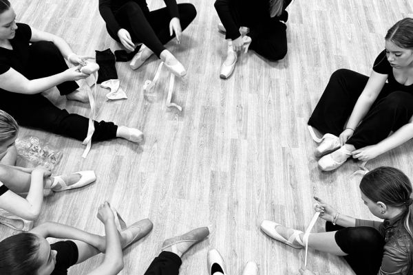 group of girls in a circle putting pointe shoes on